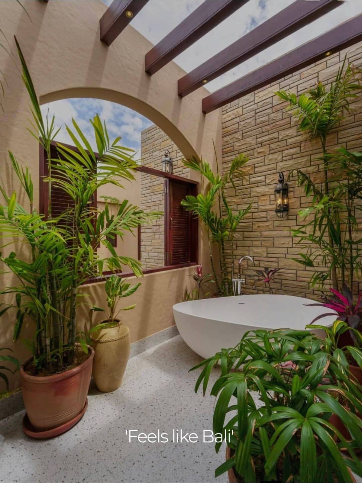Outdoor bath under a timber pergola screened by planting